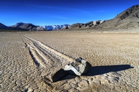 Stones leaving trails on dry lakebed.