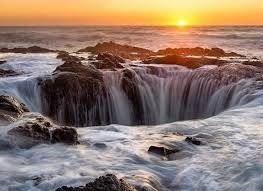 Sunset over rocky ocean waterfall that looks like a well